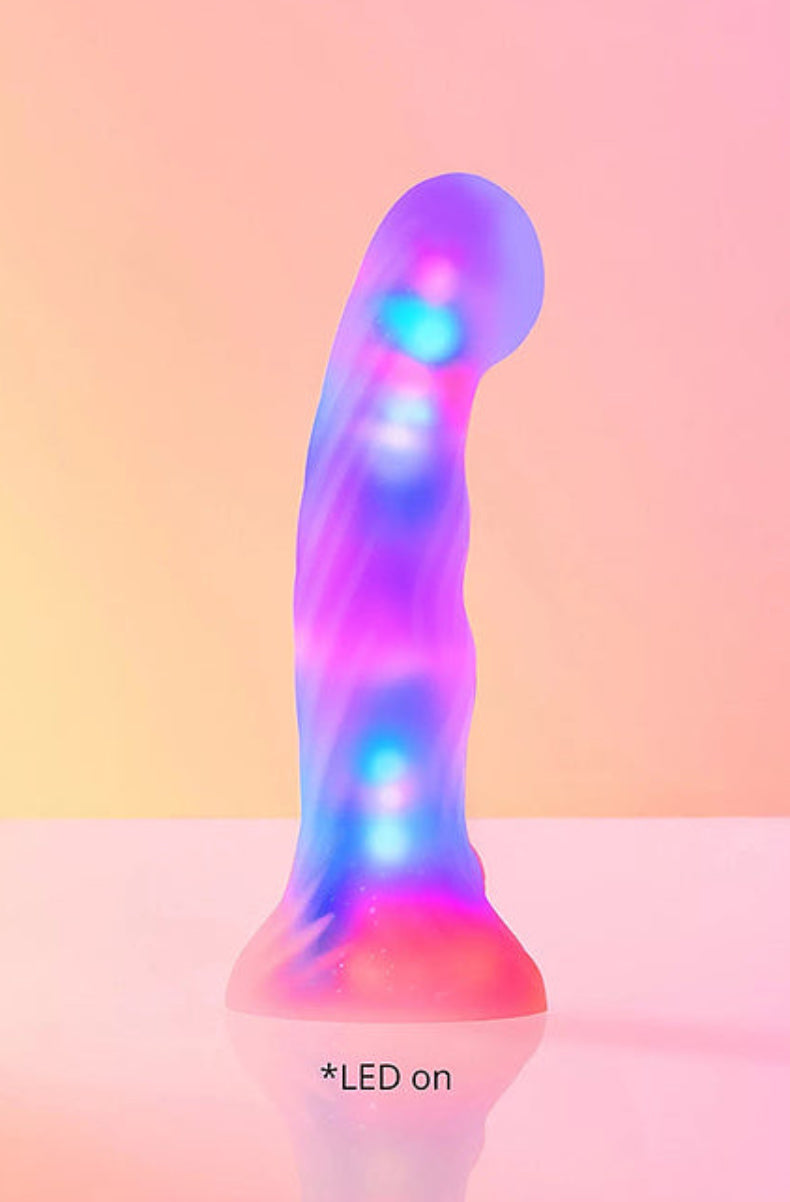 Yellow and pink LED dildo lit up in glowing purple, blue and green on a pink background
