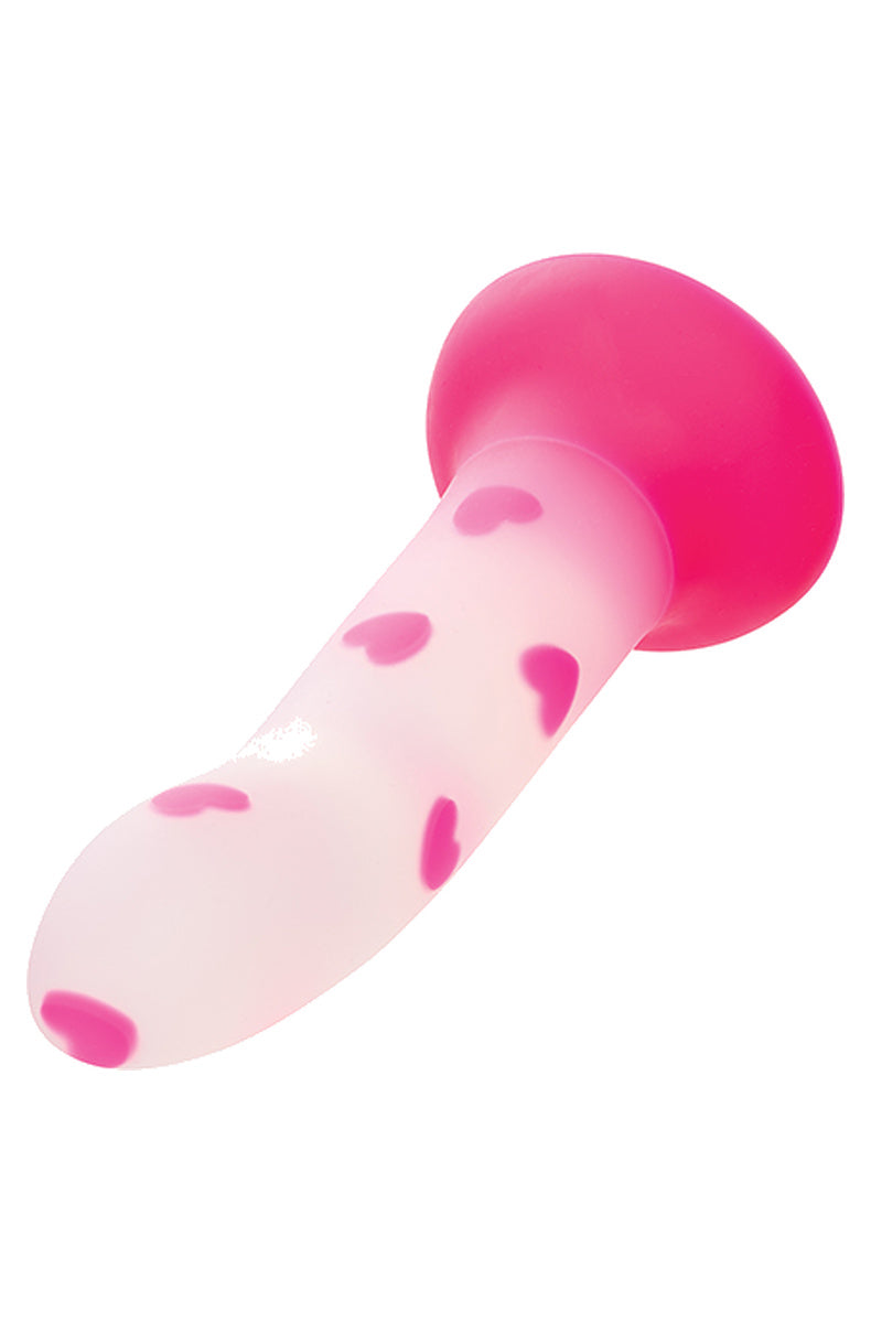 Pink heart glow in the dark dildo lying at an angle showing the hot pink suction base
