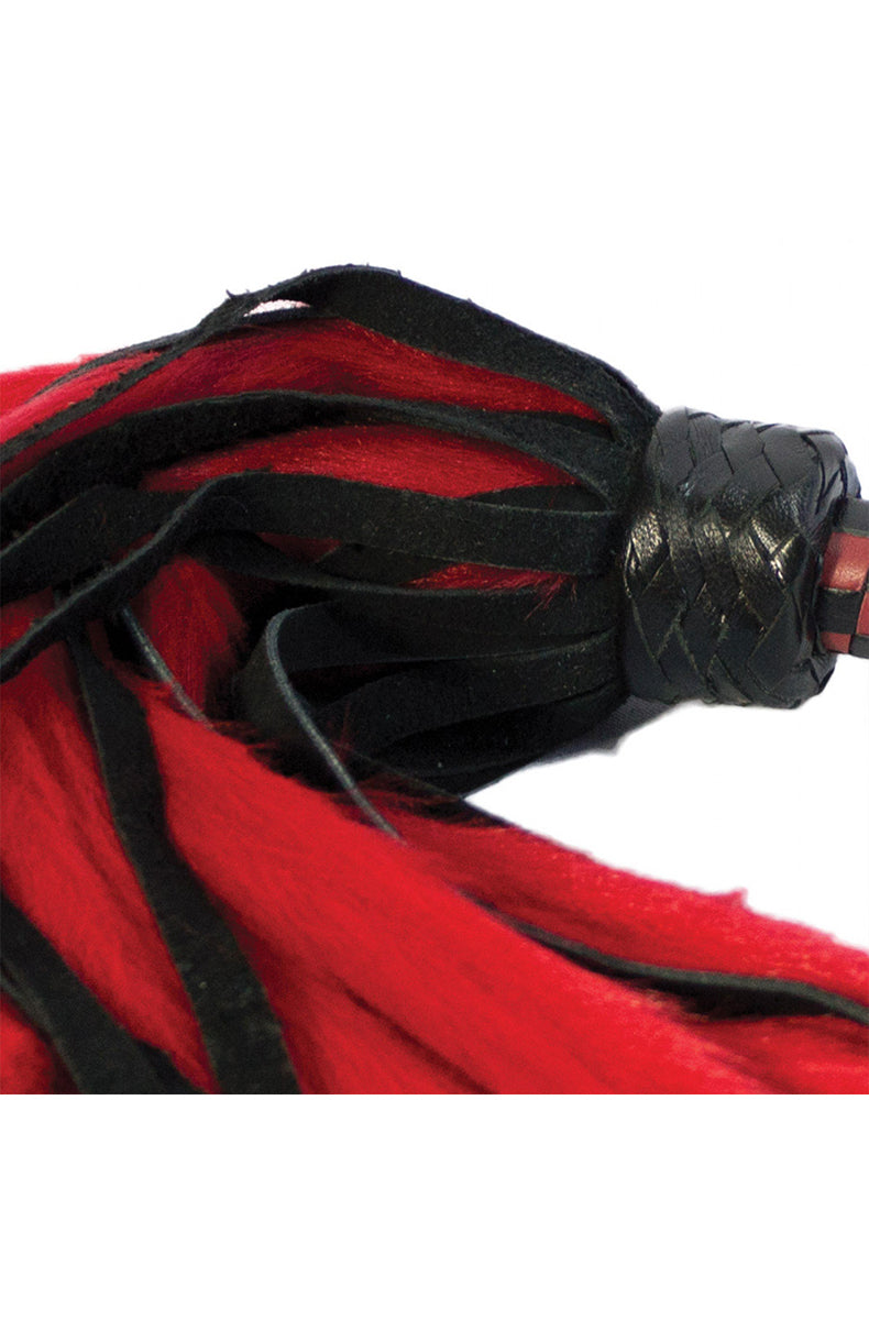 Close-up of the braided black knot where red faux-fur and black suede tails meet the red and black checkered handle.
