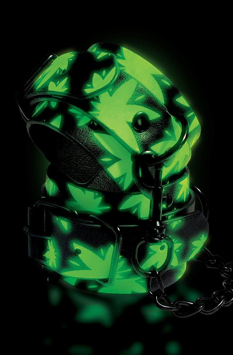 Glow-in-the-dark view of the cannabis-leaf wrist cuffs glowing green against a black background.