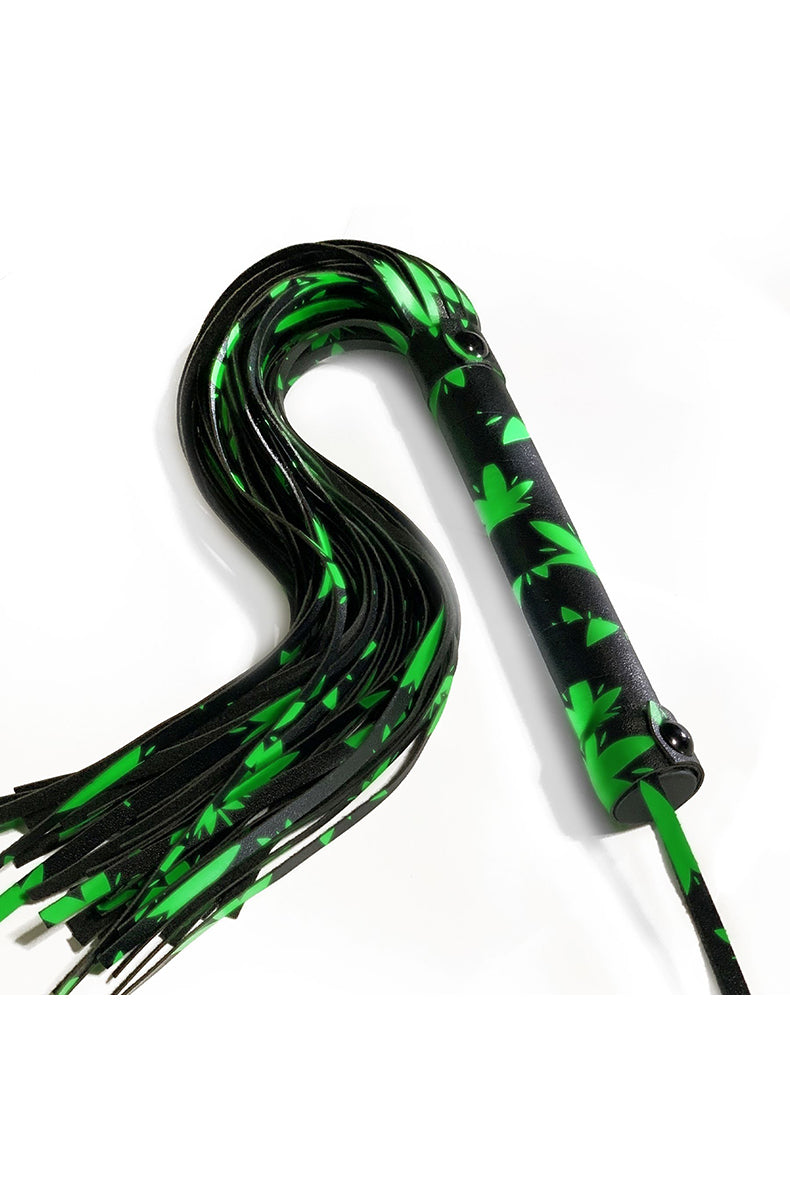 Black flogger with bright green glow-in-the-dark cannabis-leaf print falls and a matching wrapped handle with wrist cord.