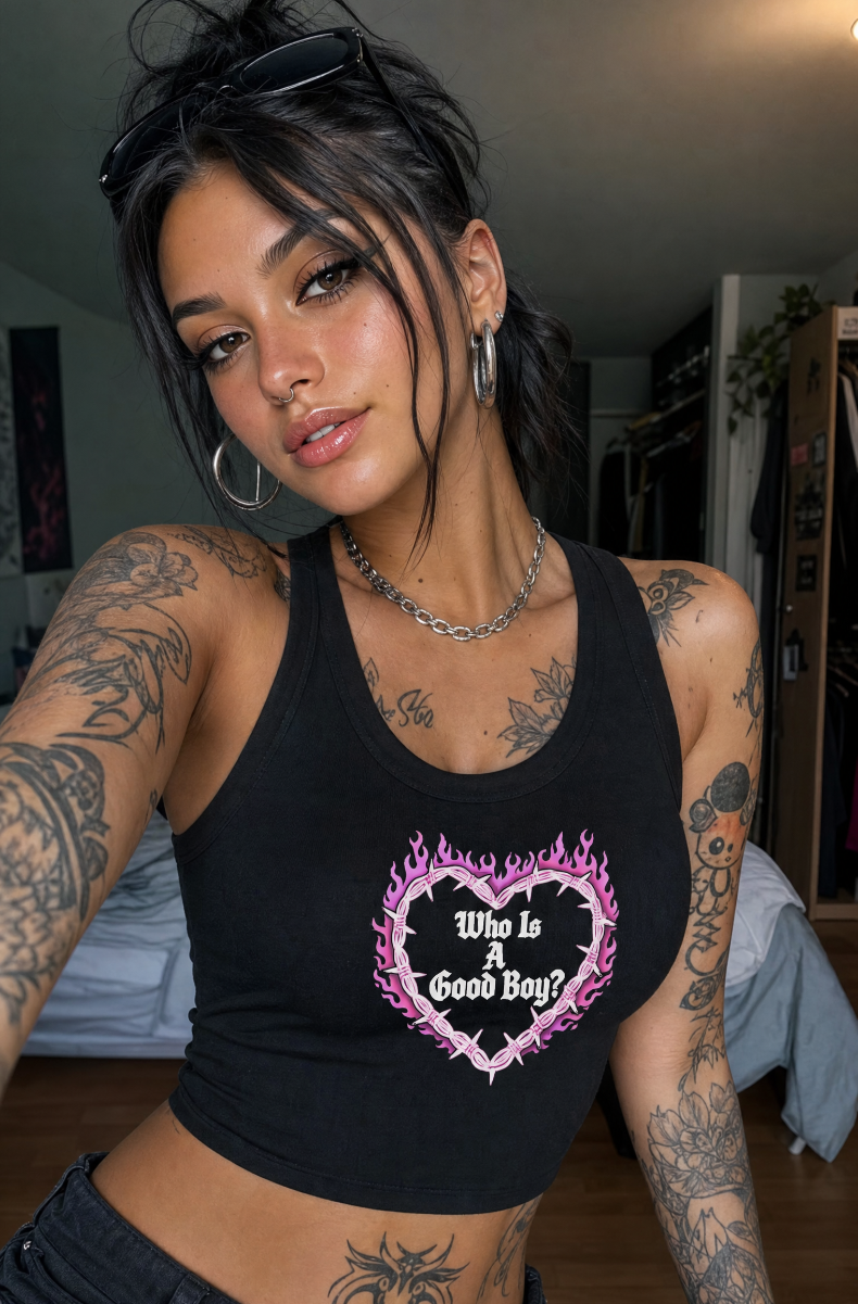 Black Who Is A Good Boy racerback tank with a pink flaming barbed-wire heart graphic, worn by a model in a bedroom.