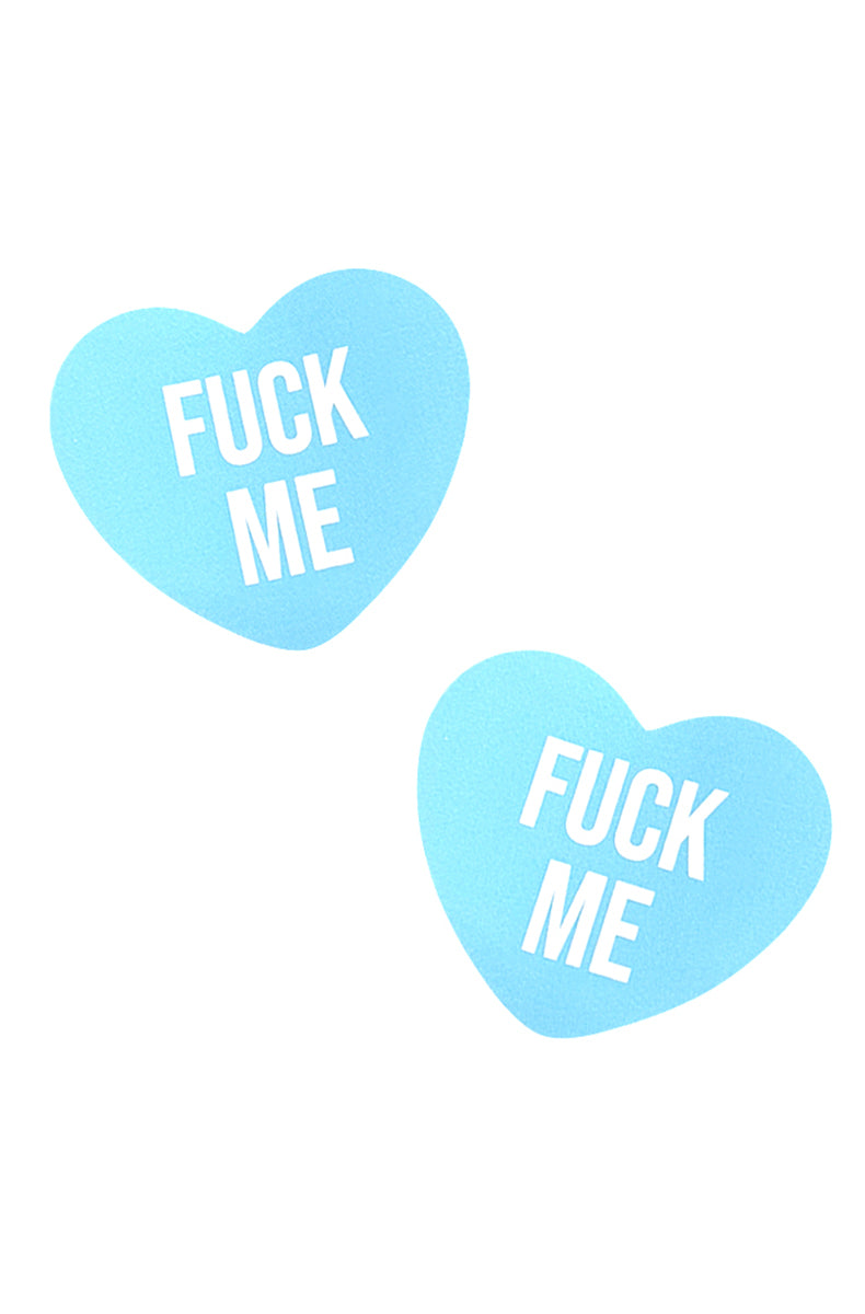 Two light-blue heart-shaped pasties with a matte candy-heart finish and "FUCK ME" in bold white block lettering.