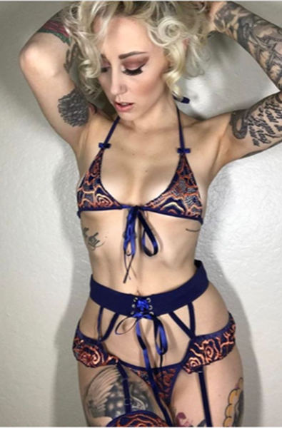 Brown and burgundy paisley-print sheer mesh triangle bralette with thin black halter straps and a small bow at the center bust, plus matching strappy garter belt with rhinestone center detail.