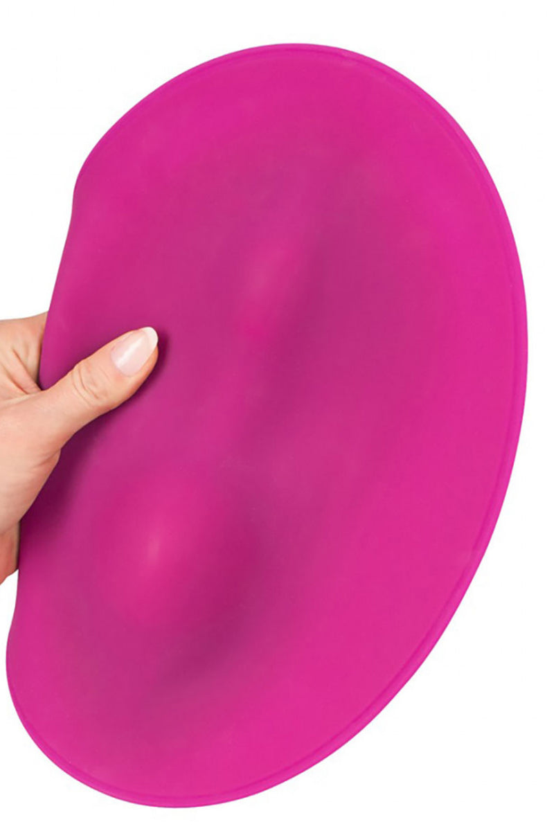 Hand holding edge of pink grinding mat to show flexibility and shaped contour