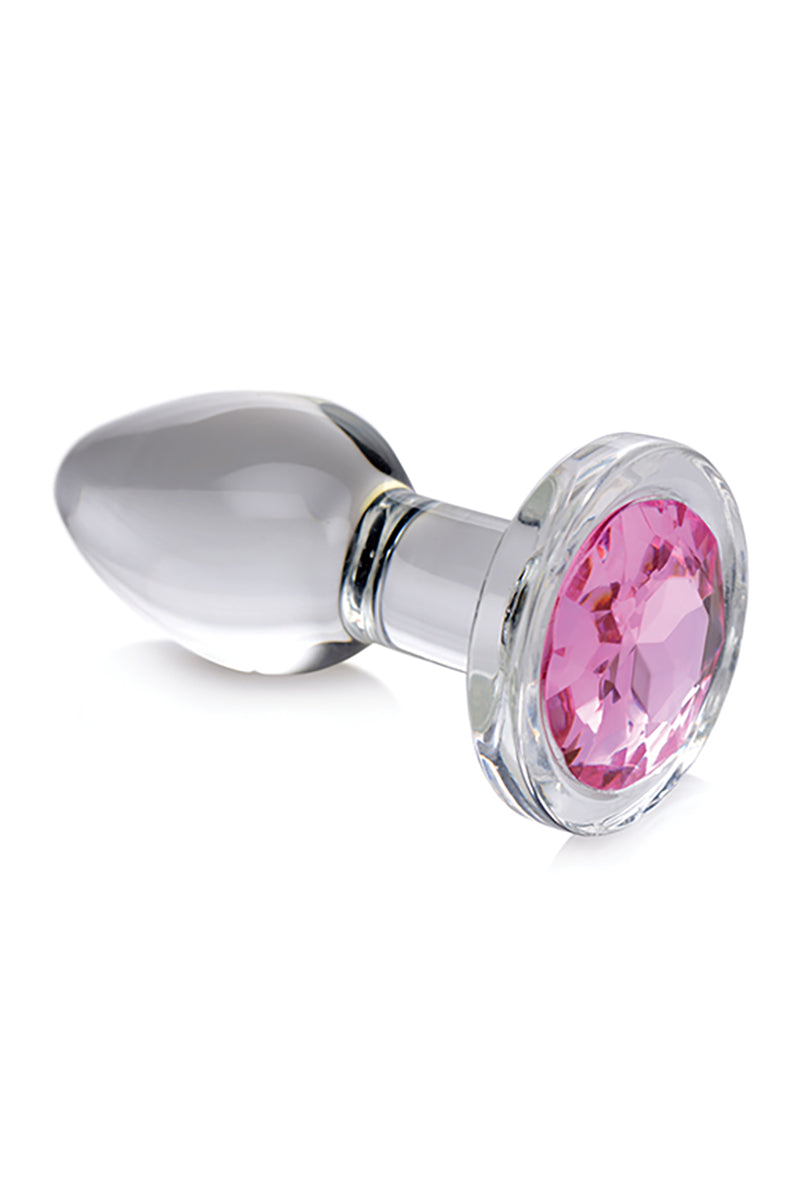 Small clear glass butt plug with a tapered shaft and a flared round base set with a faceted pink gem.
