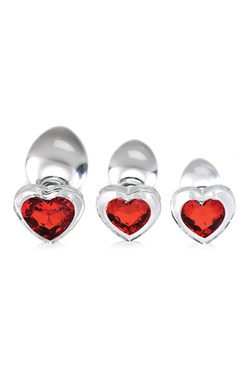 Three glass anal plugs with red heart gems in flared heart bases, graduated small to large. Booty Sparks.