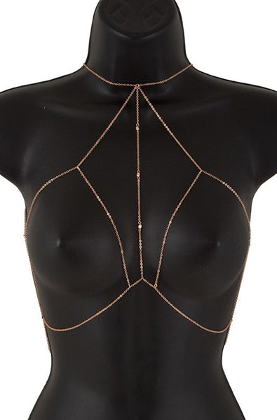 Delicate gold-tone body chain bra with single-strand chains forming open bra triangles and small rhinestone bezels along the chain, on a black bust form.