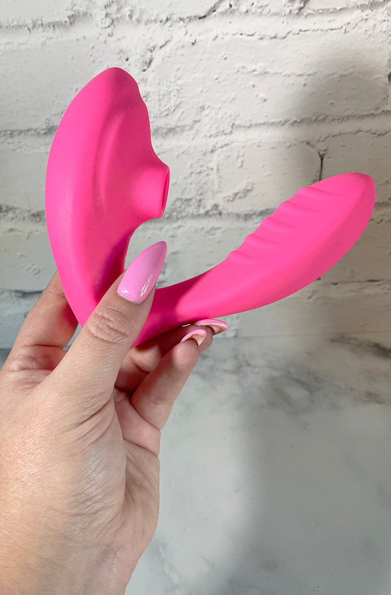 Hot pink Maya G-spot suction vibrator held in a hand for size reference.