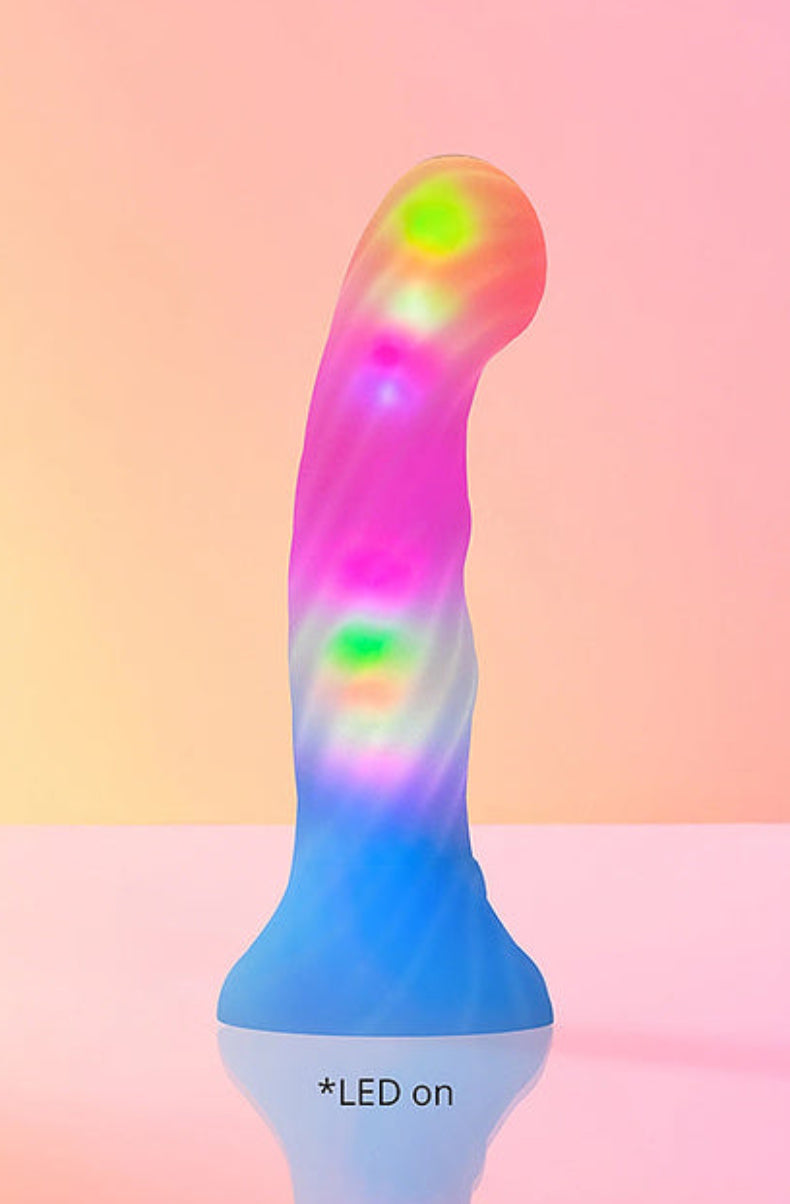 Pink and blue LED dildo lit up in glowing purple, pink and green on a pink background