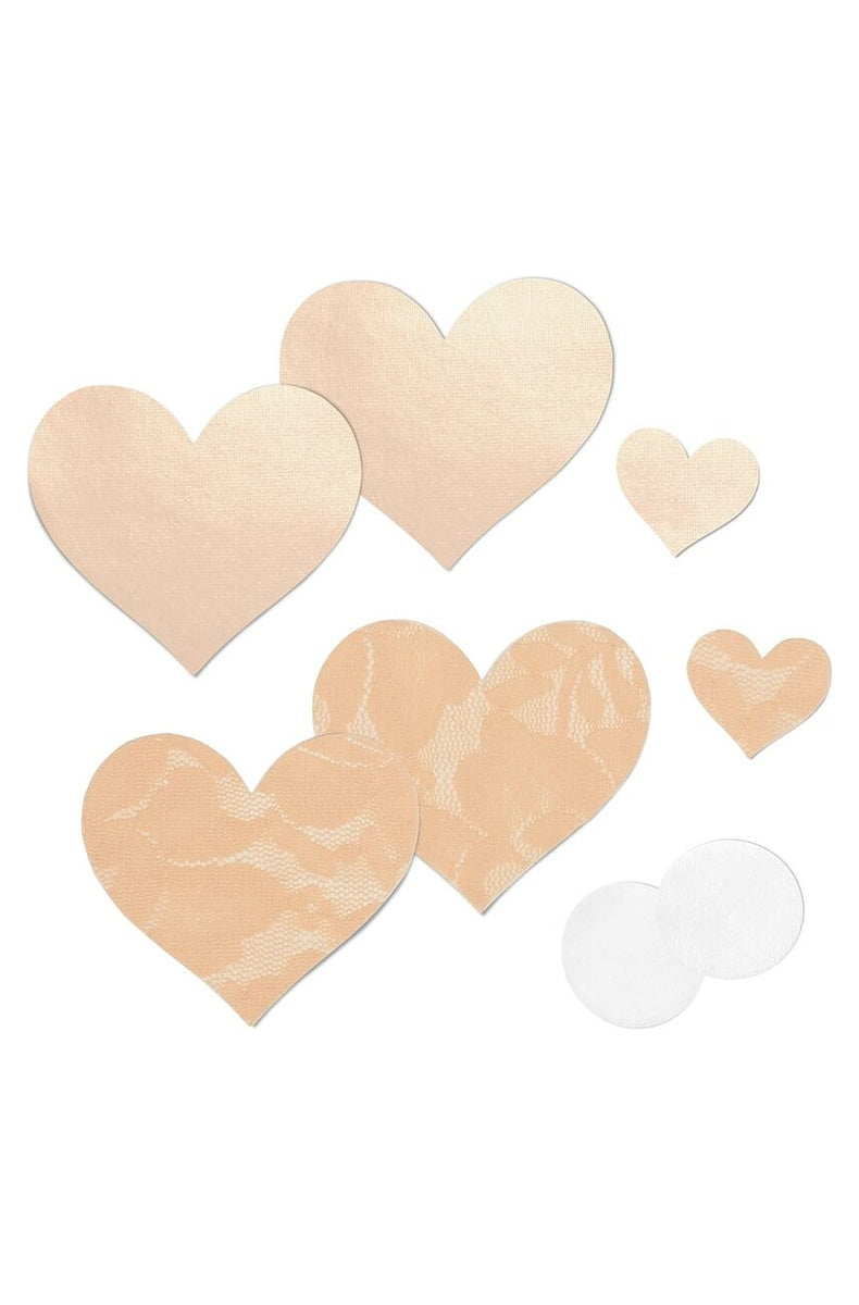 Creme lace and satin heart nipple covers laid out with nipple pads and patch tests