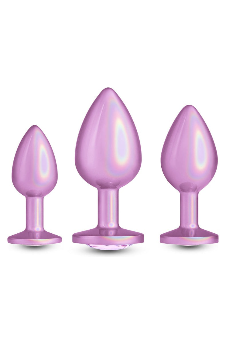 Three iridescent pink metal butt plugs in small, medium and large standing in a row