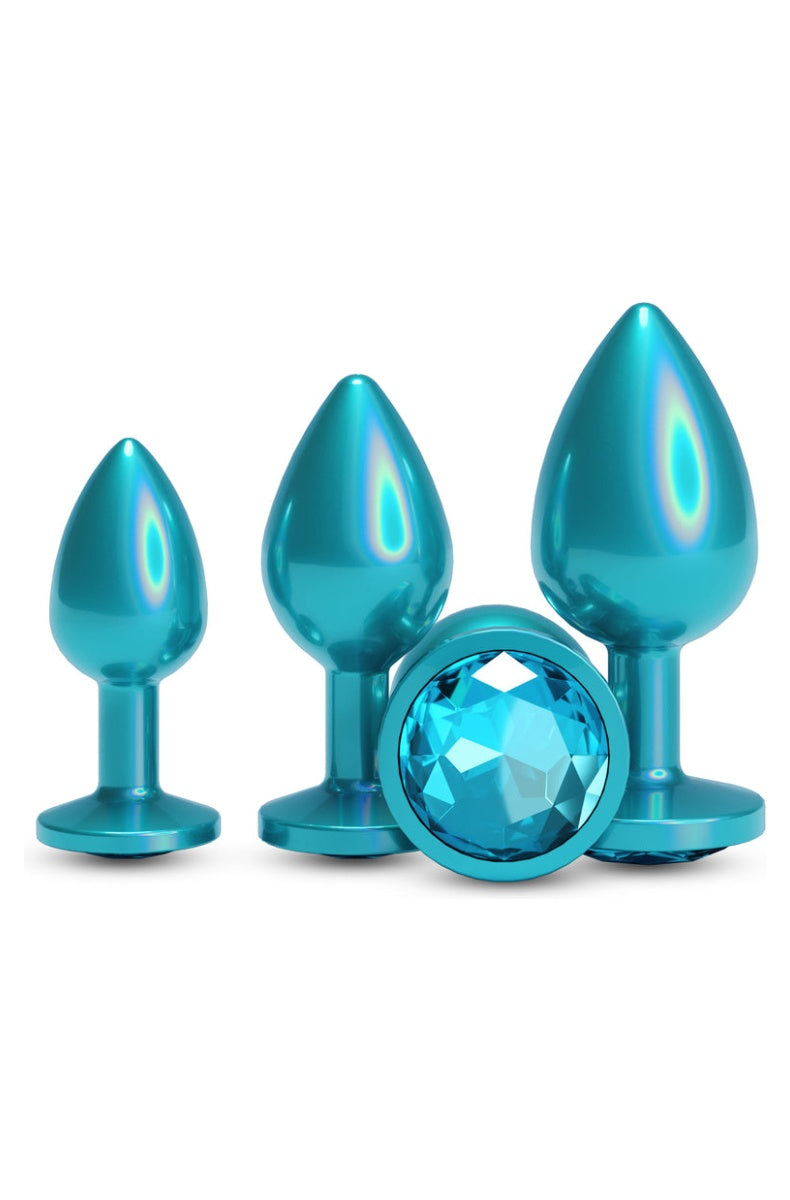 Three teal metal butt plugs in small, medium and large standing in a row, each with a round teal gem base