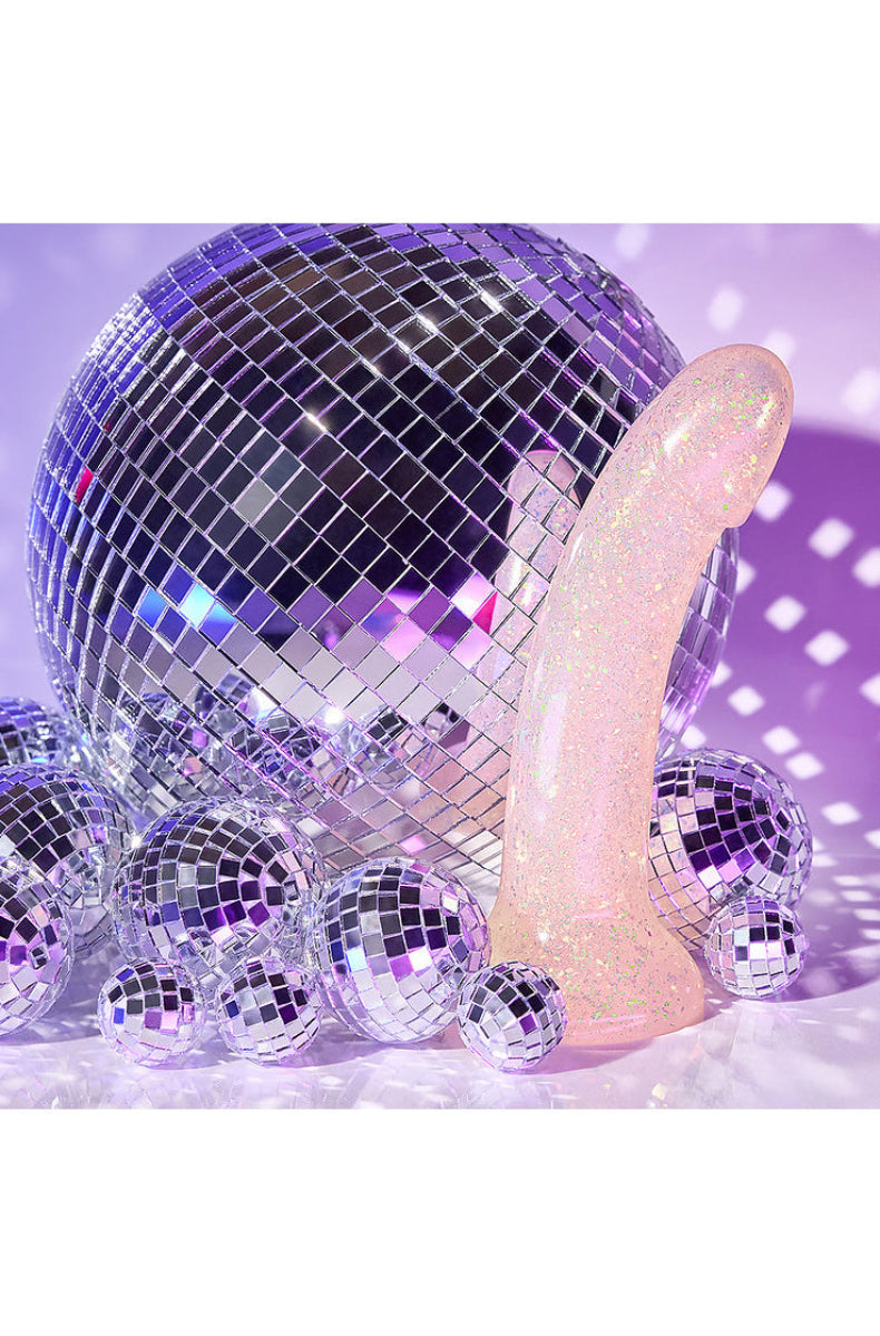 Clear gold glitter dildo leaning on a disco ball with mirror balls on a purple background