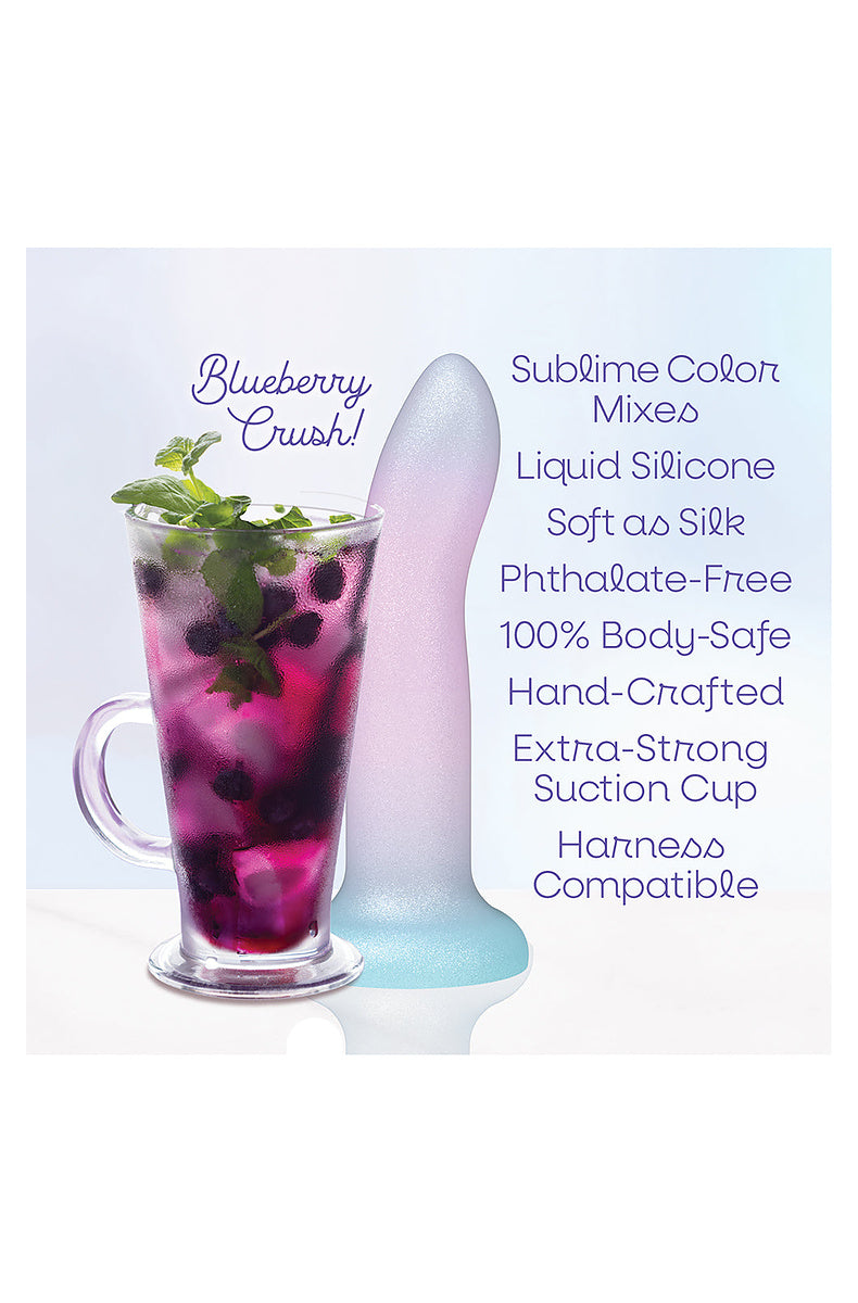 Lavender, pink and aqua ombre dildo beside a blueberry crush cocktail: liquid silicone, suction cup, harness compatible