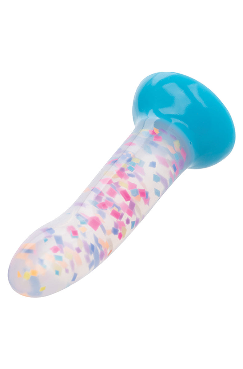 Rainbow confetti glow in the dark dildo lying at an angle showing the blue suction base