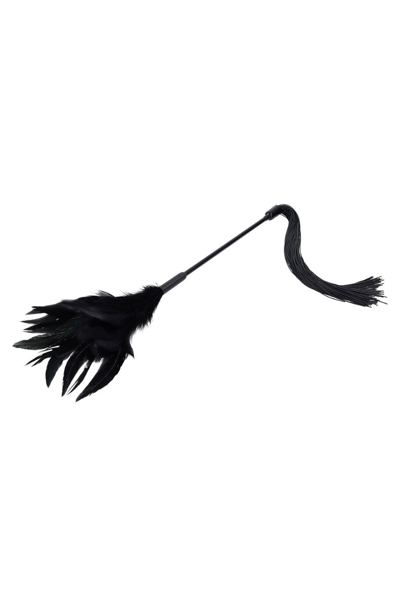 The feather tickler laid curved, showing the black feather head and the slim shaft