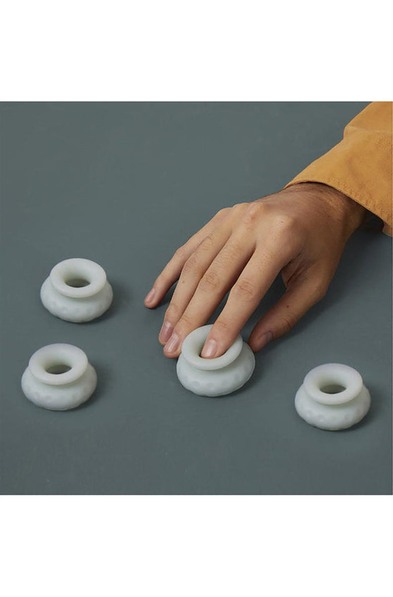 Four jade Ohnut rings laid out separately, with a hand pressing one to show how soft they are.
