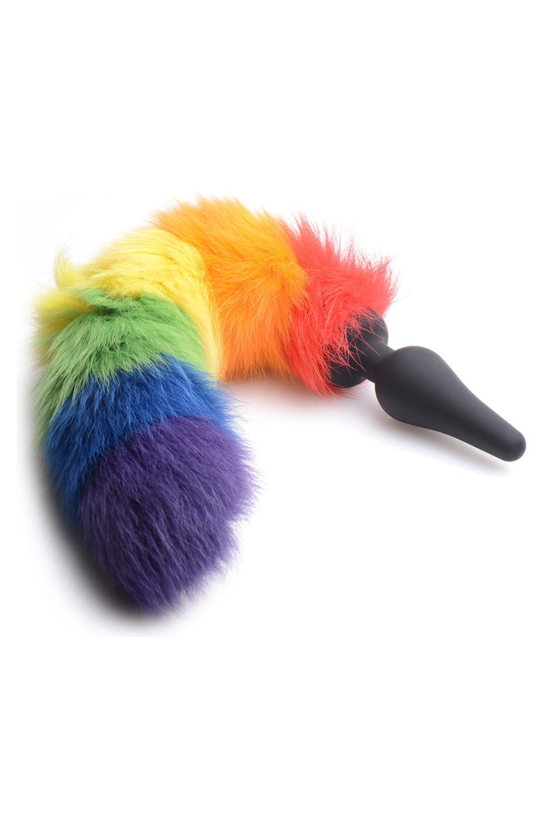 The rainbow striped faux fur tail curled, showing its full thickness against the black plug