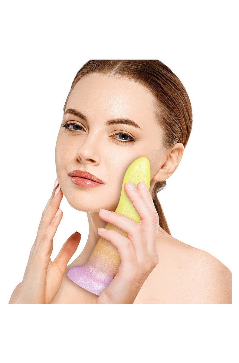 Model holding the yellow, orange and pink ombre silicone dildo against her cheek