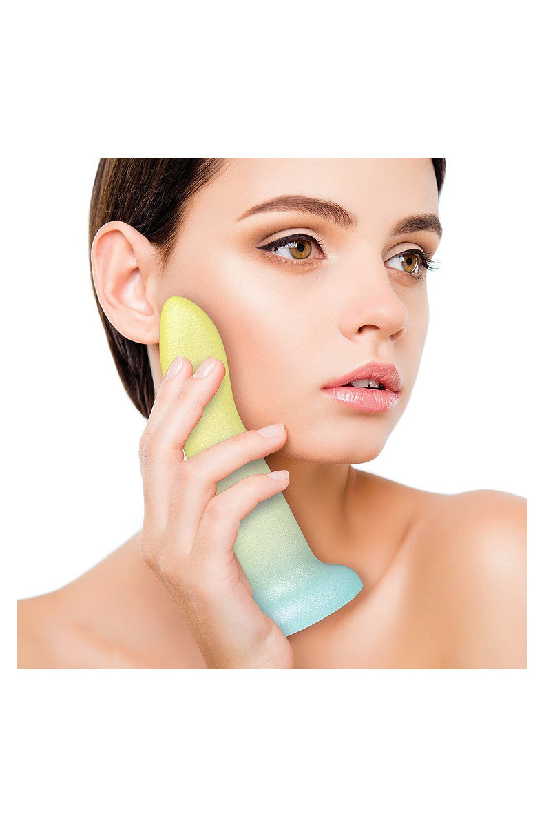 Model holding the yellow, mint and aqua ombre silicone dildo against her cheek