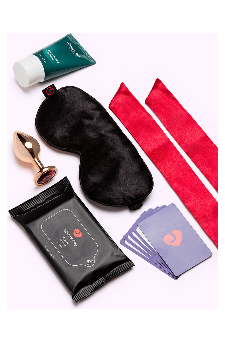 Satin blindfold, red satin restraints, jeweled plug, lube, toy wipes and sex positions cards