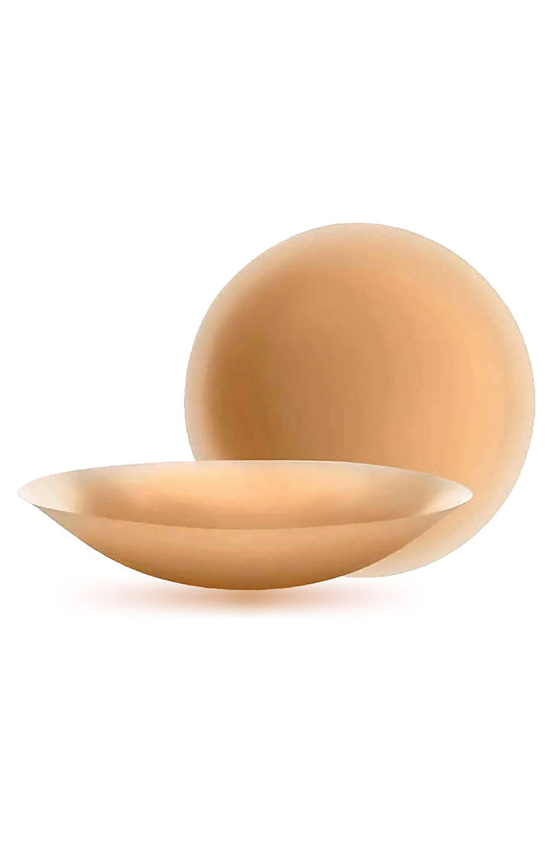 Round silicone nipple covers in the medium tone, one lying flat and one curved