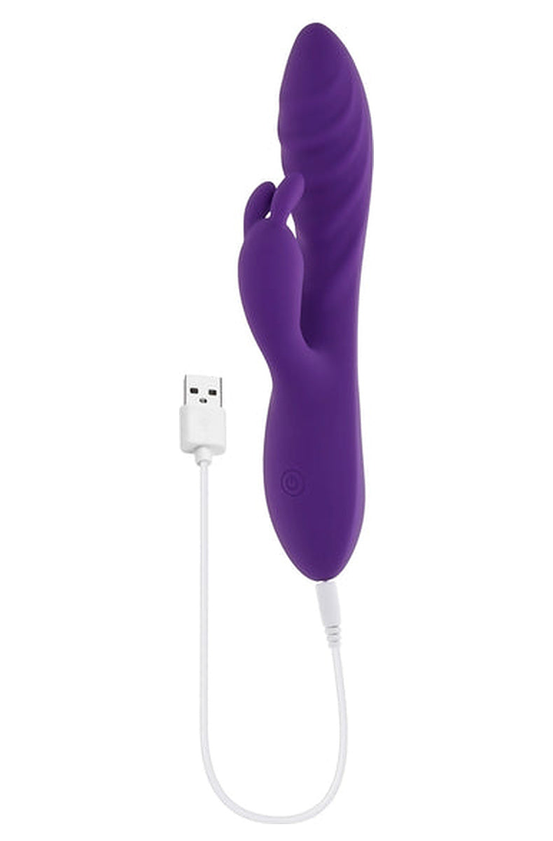Purple Wavy Rabbit vibrator with the included USB charging cable plugged into the base.