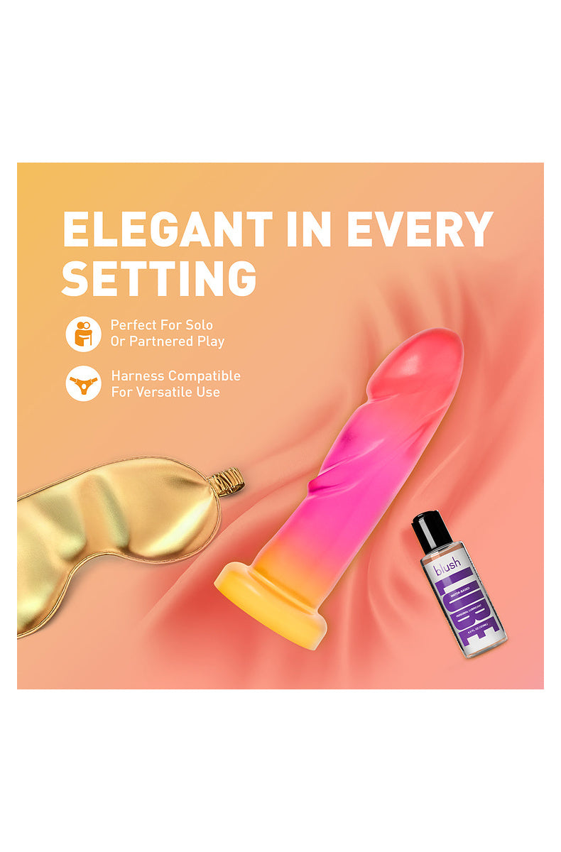 Pink and gold ombre dildo beside a satin sleep mask and lube, harness compatible for solo or partnered play