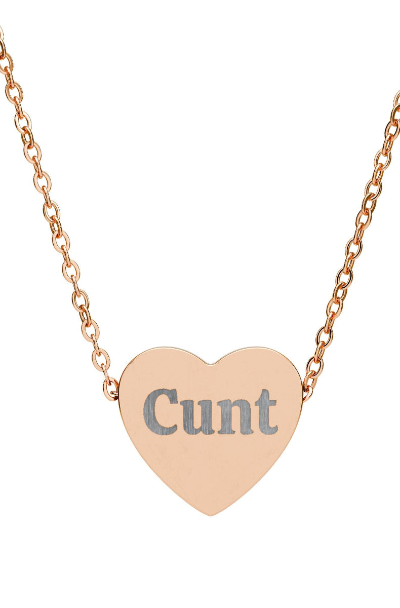 Heart-shaped pendant with the word 'Cunt' on a rose gold chain against a white background