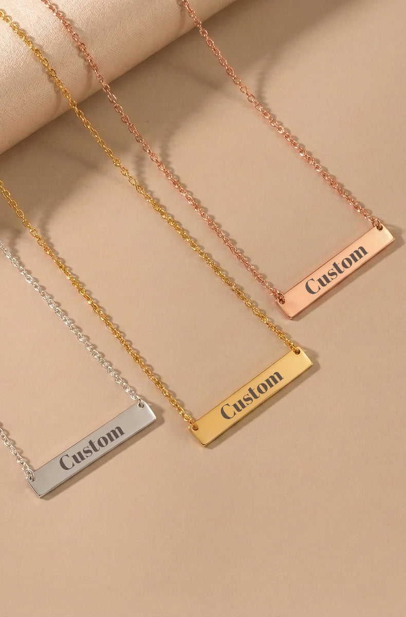 Three custom engraved bar necklaces on chains showing silver, gold, and rose gold finishes with "Custom" text