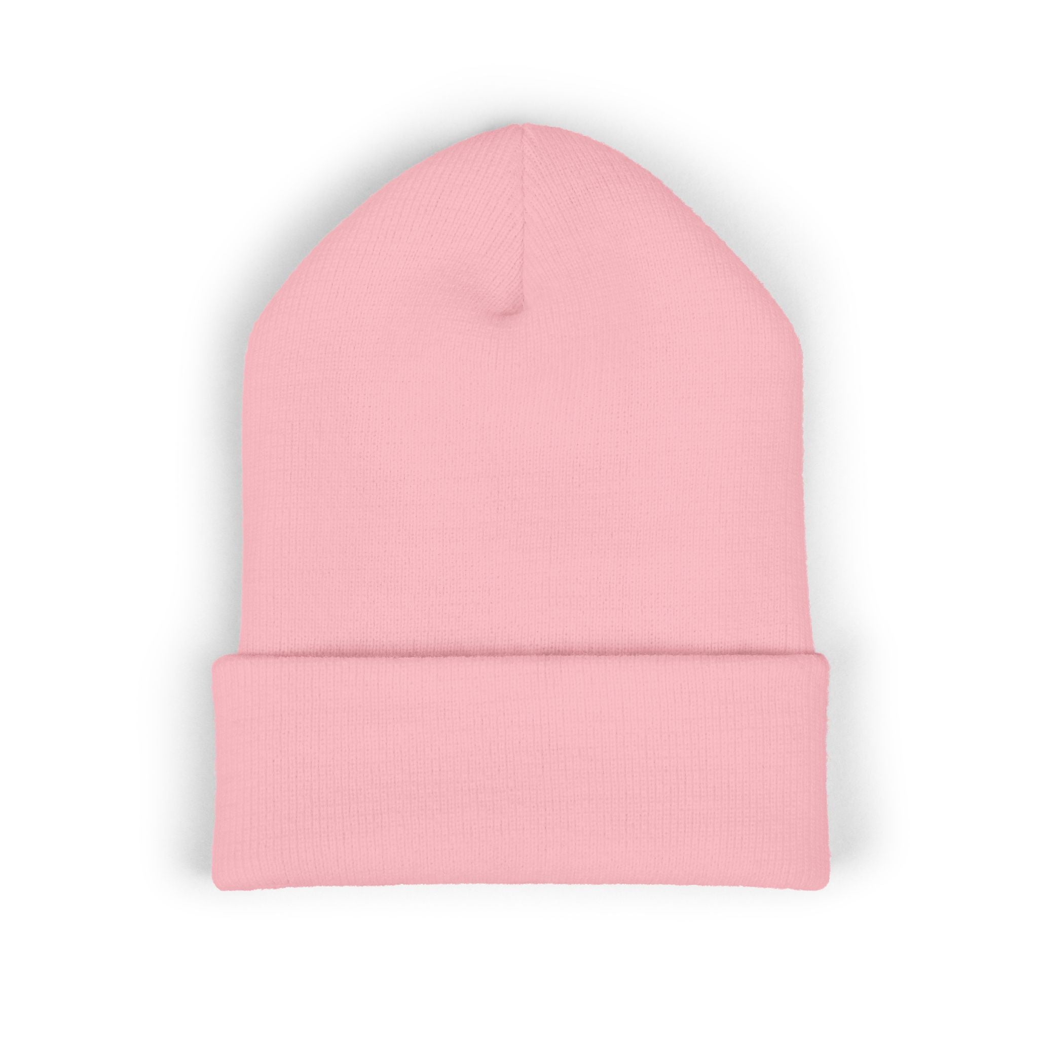 Soft pastel pink cuffed knit beanie with bold hot-pink "Brat" embroidery across the front of the cuff, worn by a model with pink hair.