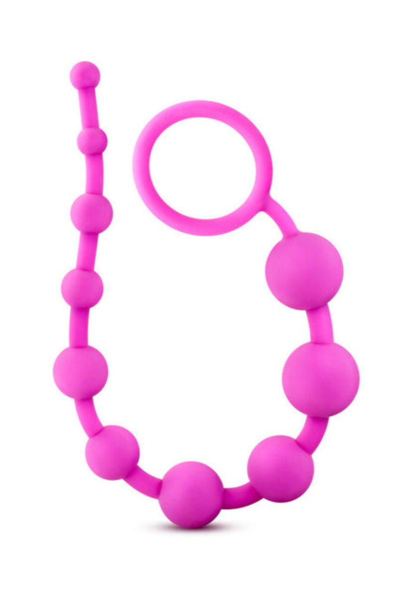 Pink silicone anal beads coiled upright with the looped ring handle near the top, on a white background.