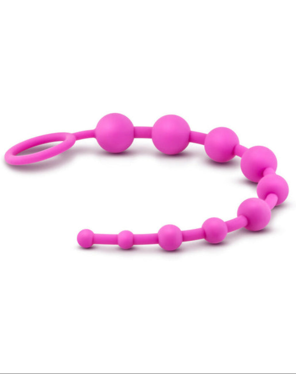 Pink silicone anal beads laid in a horizontal wave with the looped ring handle at left, on a white background.