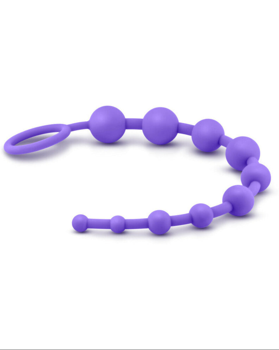 Purple silicone anal beads laid in a horizontal wave with the looped ring handle at left, on a white background.