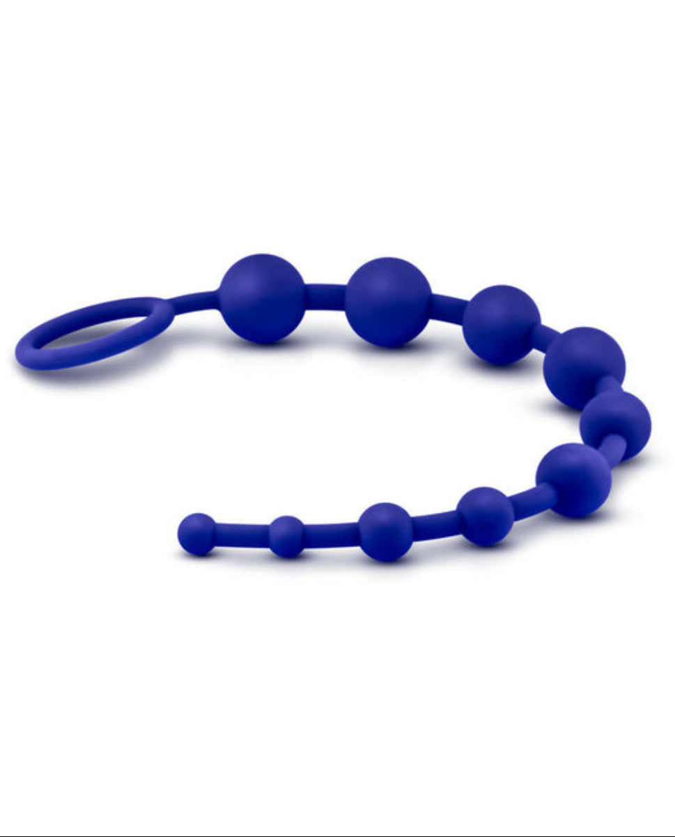 Indigo silicone anal beads laid in a horizontal wave with the looped ring handle at left, on a white background.