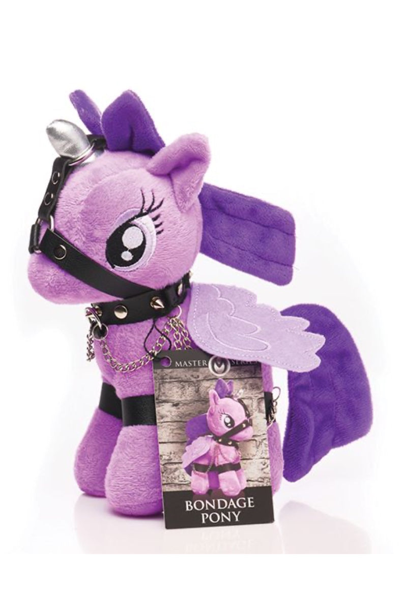 Side view of purple bondage pony plush with harness and chains on white surface with product packaging