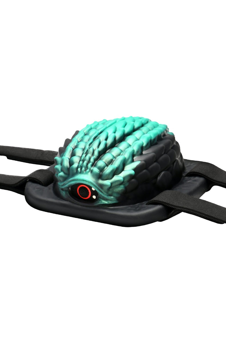 Front view of turquoise dragon-textured grinding pad with red eye detail and black adjustable straps