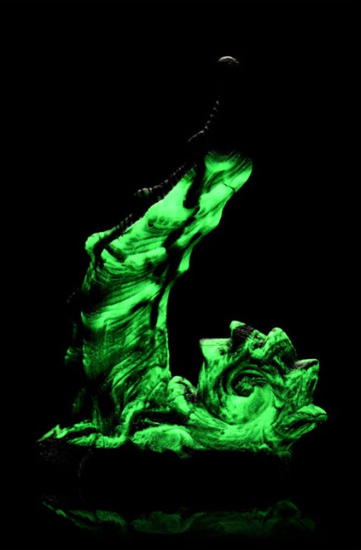 Glowing green dildo photographed in darkness showing bright green luminescent effect