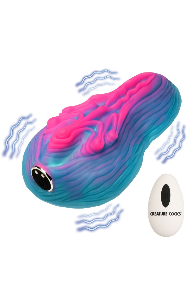 Front view of pink-teal-purple gradient silicone alien vulva grinder with white remote control on white background