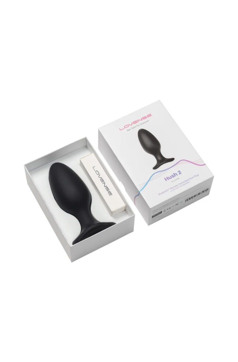 Opened white retail box showing black butt plug nested in foam insert with charging cable