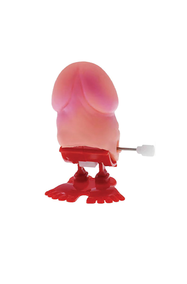 Pink wind-up plastic penis-shaped toy with a turn key on the side, sized to fit in the palm for tabletop jumping.