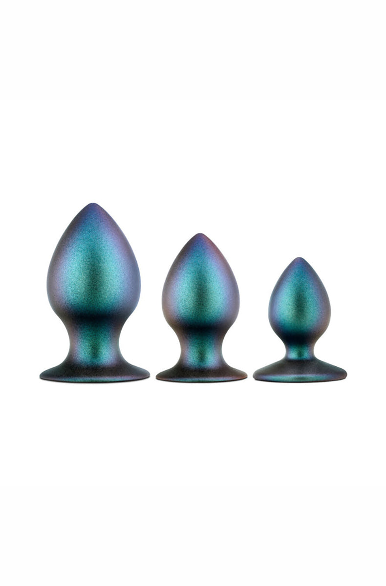 Three iridescent teal anal plugs in graduated sizes standing in a row, each with a tapered tip and flared base, on white.