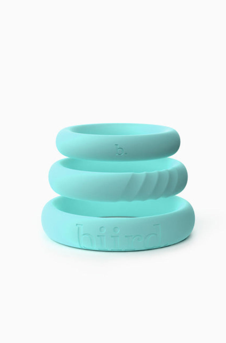 Three mint silicone cock rings stacked, smooth bands in graduated sizes, one with a textured band, on a white background.