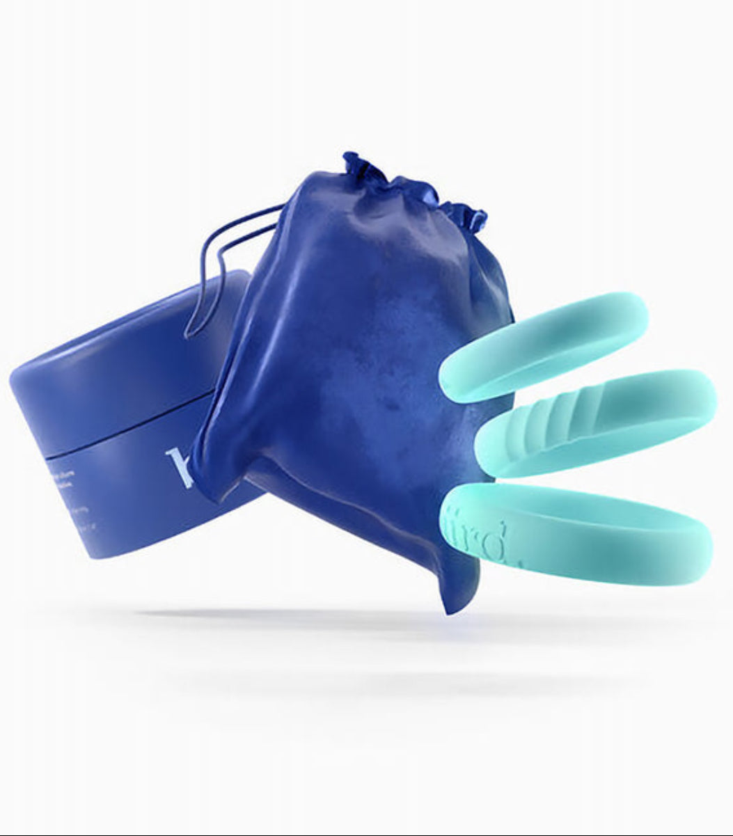 Three mint silicone cock rings fanned out with a navy velvet pouch and Biird box, on a white background.