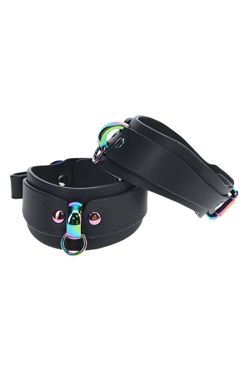 Stacked pair of black bonded leather ankle cuffs showing the iridescent rainbow D-ring and rivet detail.