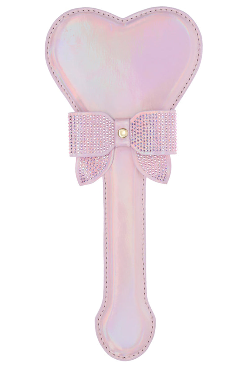 Pink iridescent bonded leather heart-shaped paddle with a rhinestone bow wrapped around the neck above the handle.