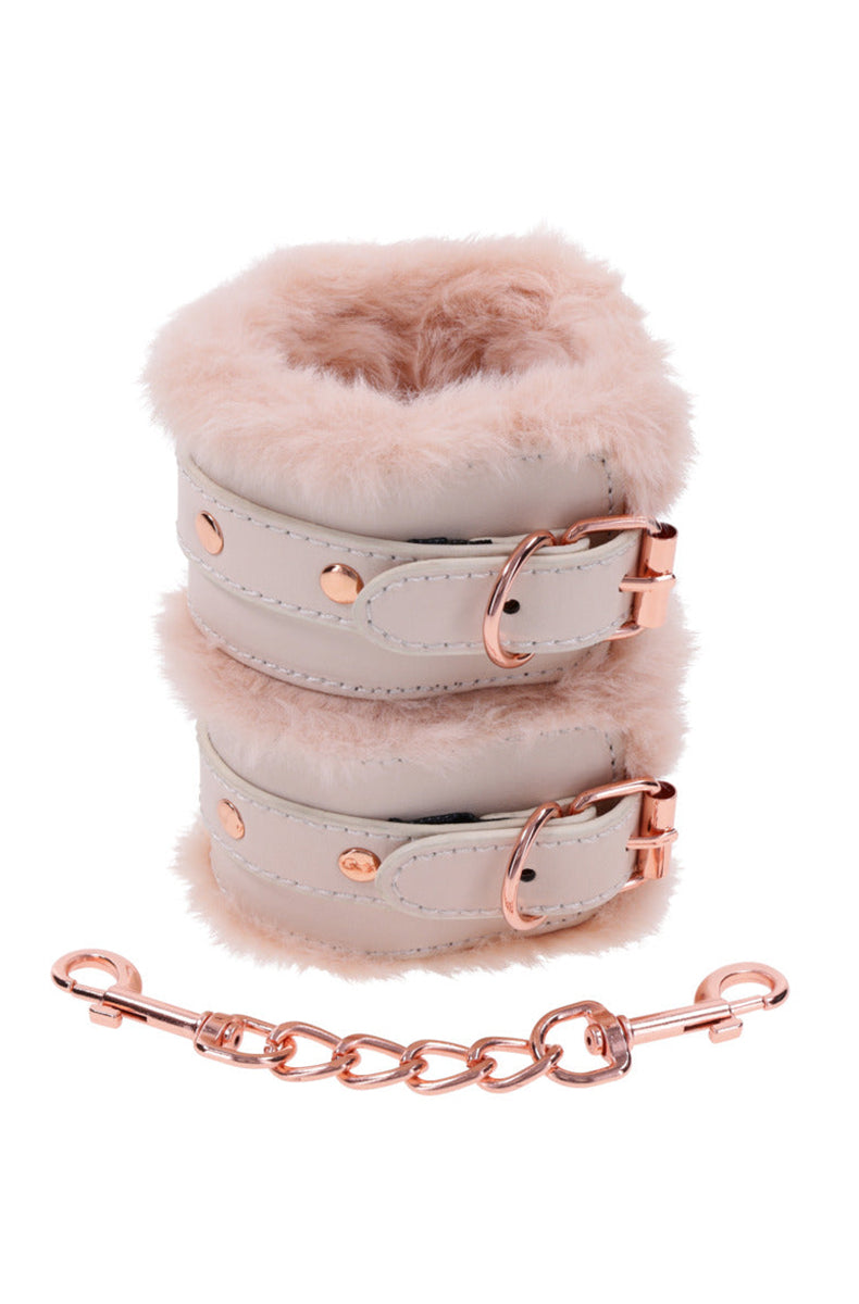 Stacked pair of pale cream faux leather wrist cuffs with peach faux fur lining and rose-gold nickel-free hardware.