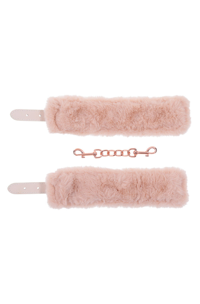 Detail of peach faux fur cuff linings with a rose-gold chain and snap clips between them.
