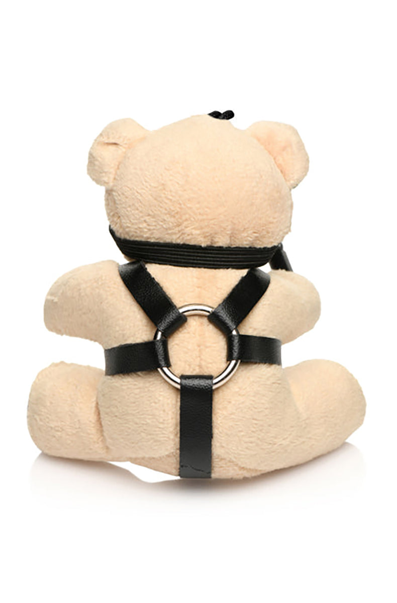 Close-up of black eye mask and PU harness with silver O-ring on tan plush teddy bear keychain.